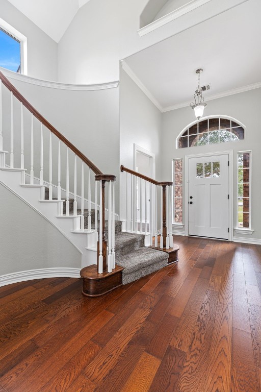 entrance foyer featuring hardwood / wood-style flooring, crown molding, and high vaulted ceiling