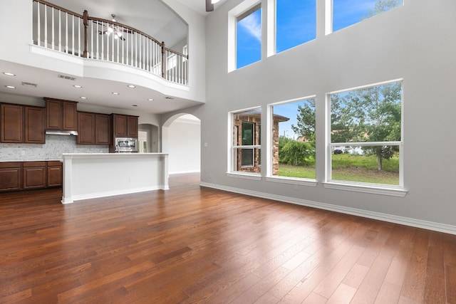 unfurnished living room featuring a towering ceiling and dark wood-type flooring