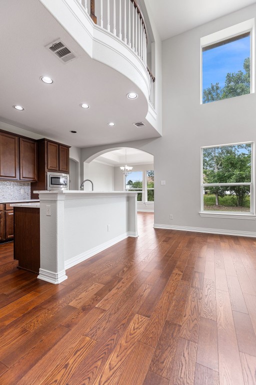 kitchen with dark hardwood / wood-style flooring, stainless steel microwave, a towering ceiling, and a wealth of natural light