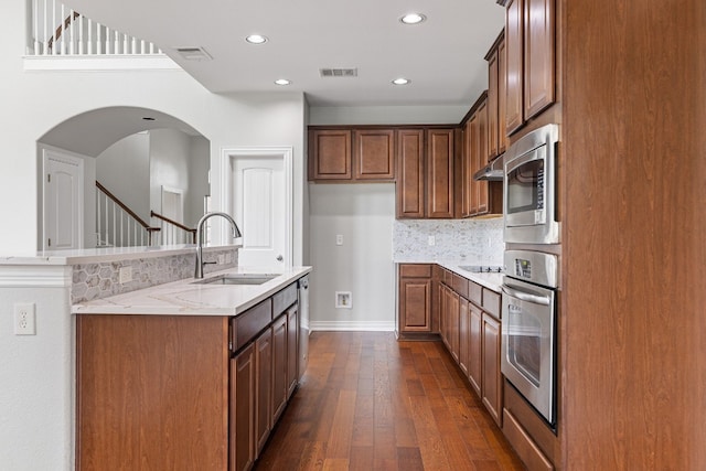 kitchen featuring sink, tasteful backsplash, light stone counters, dark hardwood / wood-style flooring, and appliances with stainless steel finishes