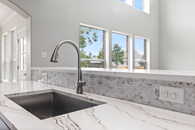 room details with light stone countertops, tasteful backsplash, ornamental molding, and sink