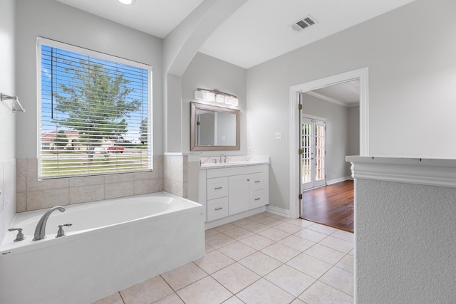 bathroom with tile patterned flooring, vanity, a bath, and crown molding