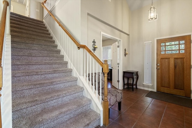 entryway with a high ceiling and dark tile patterned flooring