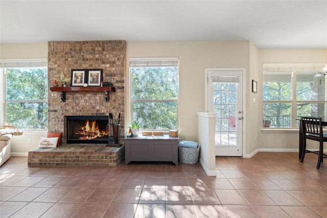 tiled living area with a wealth of natural light, a brick fireplace, and baseboards