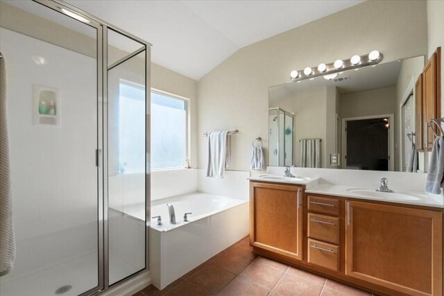 bathroom with vaulted ceiling, tile patterned flooring, a sink, and a shower stall