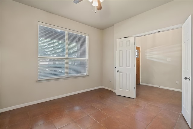 spare room with ceiling fan, light tile patterned flooring, and baseboards