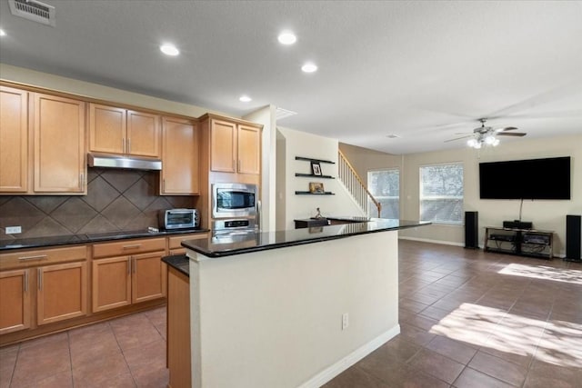 kitchen with visible vents, dark countertops, open floor plan, stainless steel appliances, and under cabinet range hood