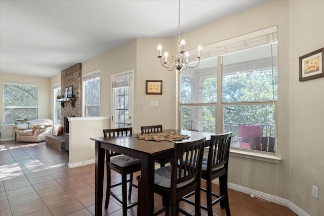 tiled dining space featuring a large fireplace, baseboards, and an inviting chandelier