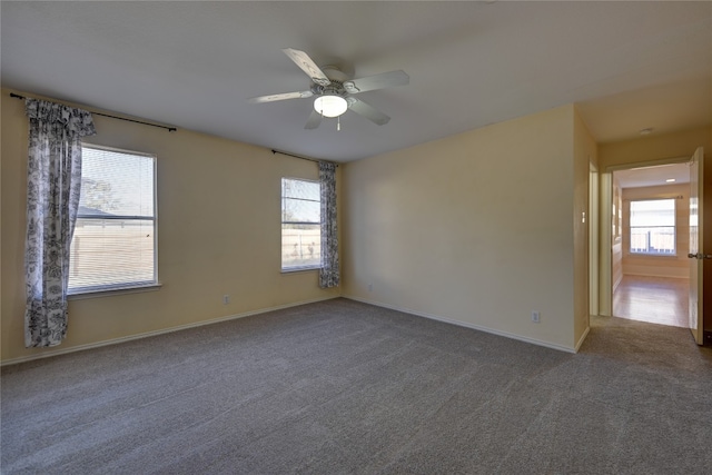 empty room featuring dark carpet, ceiling fan, and a healthy amount of sunlight