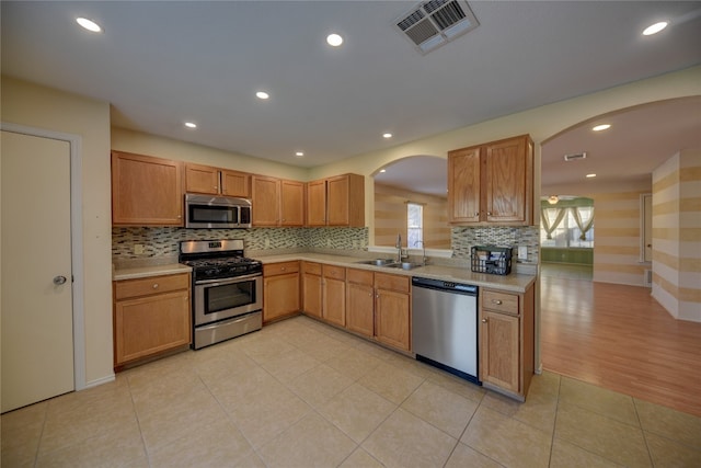 kitchen featuring decorative backsplash, light tile patterned floors, sink, and appliances with stainless steel finishes