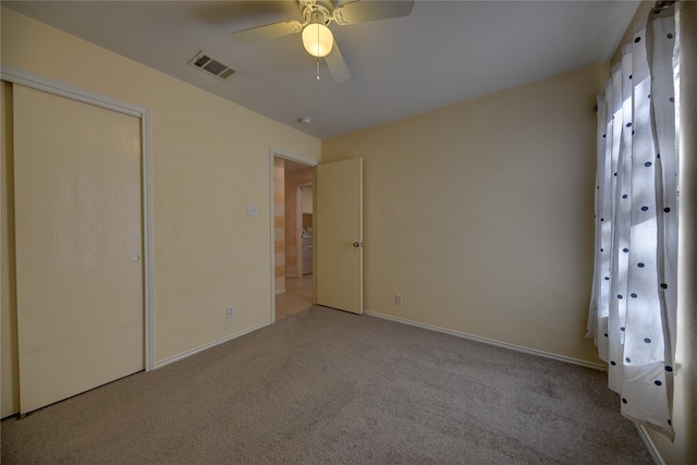 unfurnished bedroom featuring carpet flooring, washer / clothes dryer, ceiling fan, and a closet