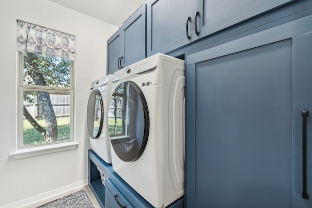 clothes washing area featuring washer and dryer and cabinets