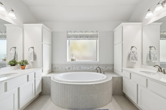 bathroom featuring vanity, tile patterned flooring, a relaxing tiled tub, and vaulted ceiling