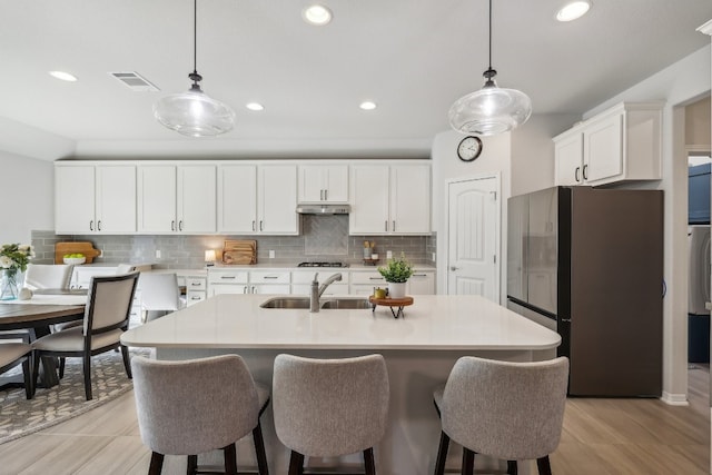 kitchen with white cabinets, sink, decorative backsplash, appliances with stainless steel finishes, and decorative light fixtures