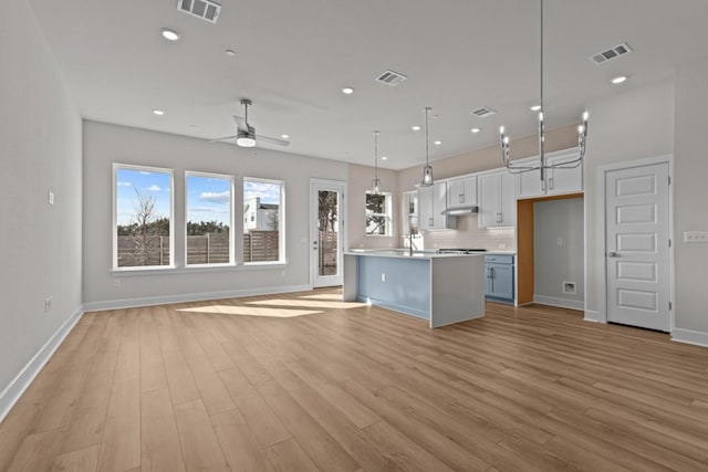 kitchen featuring open floor plan, light wood finished floors, visible vents, and under cabinet range hood