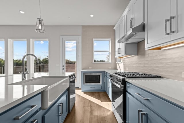 kitchen with stainless steel gas range, built in microwave, light countertops, and under cabinet range hood