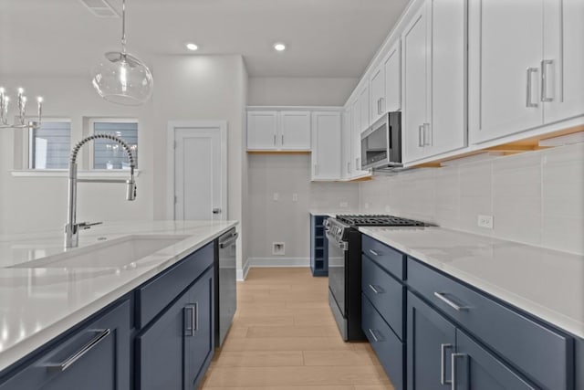 706 Terrier Trl, Austin, TX 78745 - kitchen featuring appliances with stainless steel finishes, white cabinets, light wood-style flooring, hanging light fixtures, and tasteful backsplash