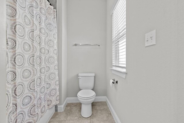 bathroom with tile patterned floors, shower / tub combo, and toilet