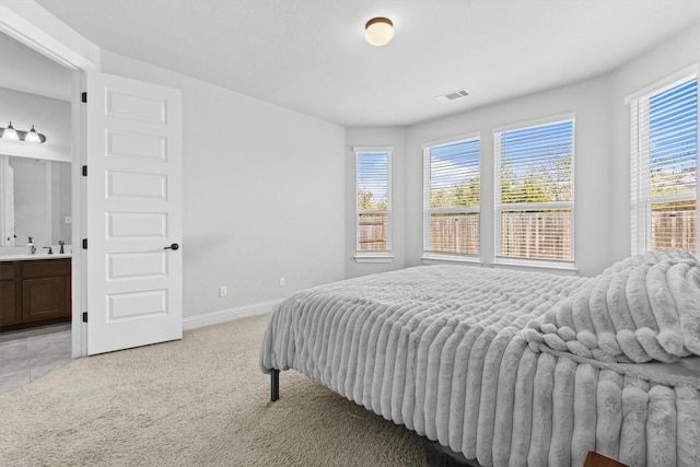 carpeted bedroom with sink and ensuite bath