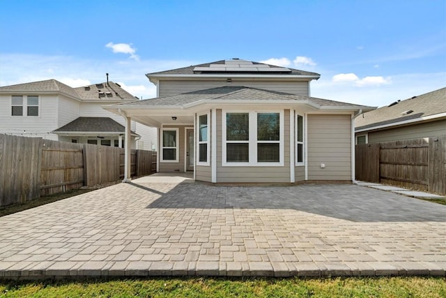 back of property featuring solar panels and a patio area