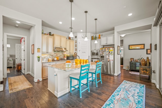 kitchen with stainless steel appliances, a kitchen breakfast bar, light stone countertops, an island with sink, and decorative light fixtures