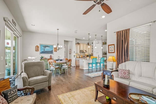 living room with ceiling fan with notable chandelier and wood-type flooring