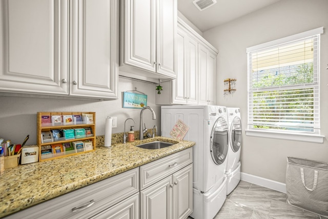 laundry room with cabinets, independent washer and dryer, and sink