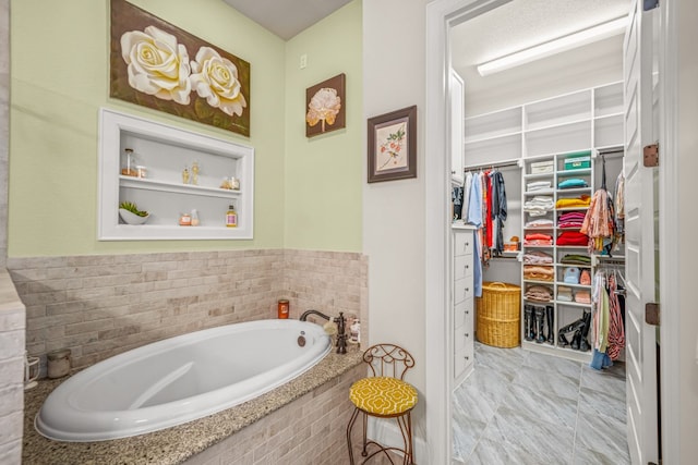 bathroom featuring tiled tub and built in shelves