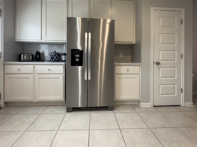 kitchen with white cabinets, decorative backsplash, light tile patterned floors, and stainless steel refrigerator with ice dispenser