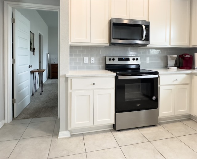 kitchen featuring backsplash, white cabinetry, light tile patterned floors, and stainless steel appliances