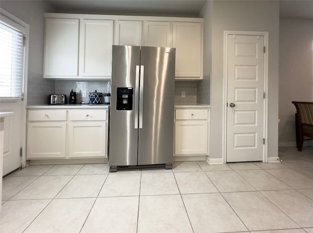 kitchen with backsplash, stainless steel fridge with ice dispenser, white cabinets, and light tile patterned floors