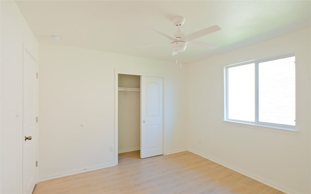 unfurnished bedroom featuring ceiling fan, a closet, and light wood-type flooring