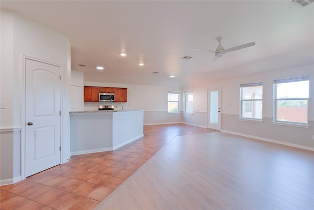 unfurnished living room with ceiling fan, light hardwood / wood-style floors, and sink