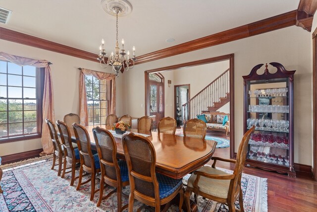 dining area with crown molding, dark wood-type flooring, and a notable chandelier