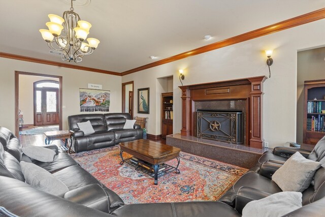 living room featuring an inviting chandelier, crown molding, and a premium fireplace