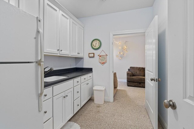 1092 Fm 3000, Elgin, TX 78621 - kitchen featuring freestanding refrigerator, a sink, dark countertops, white cabinetry, and baseboards