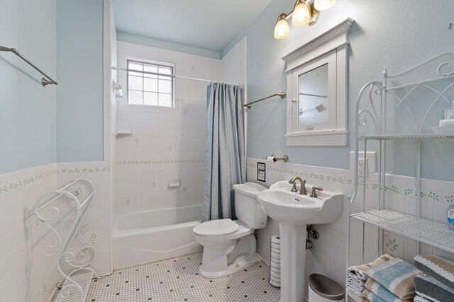 bathroom featuring tile patterned floors, toilet, tile walls, and shower / tub combo with curtain