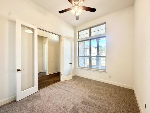 spare room with dark colored carpet, ceiling fan, and french doors