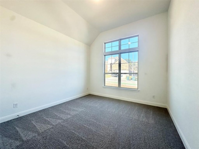 empty room with dark colored carpet and vaulted ceiling