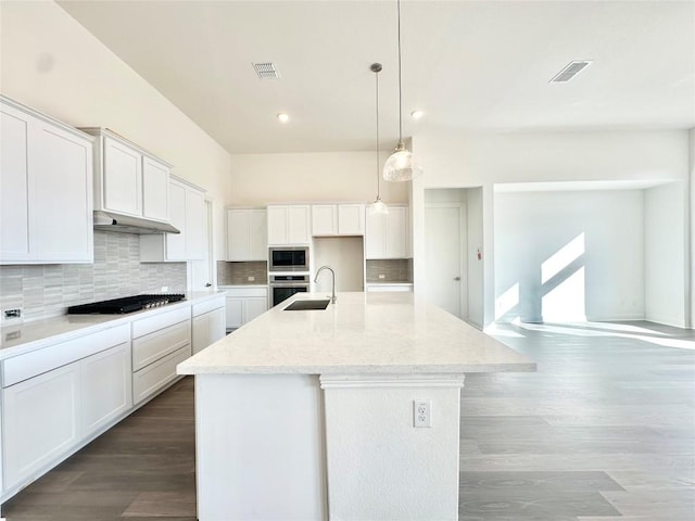 kitchen with white cabinetry, light stone countertops, hanging light fixtures, a kitchen island with sink, and appliances with stainless steel finishes