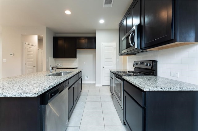 kitchen featuring sink, decorative backsplash, light stone countertops, light tile patterned flooring, and stainless steel appliances