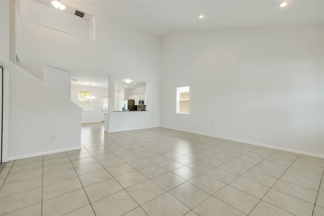 unfurnished living room featuring light tile patterned floors, high vaulted ceiling, and an inviting chandelier