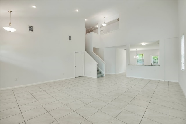 spare room with light tile patterned flooring and a towering ceiling