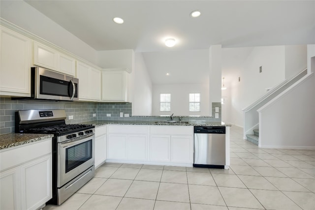 kitchen featuring sink, light tile patterned floors, dark stone counters, white cabinets, and appliances with stainless steel finishes