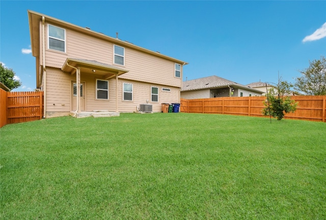 rear view of property with central AC unit and a lawn