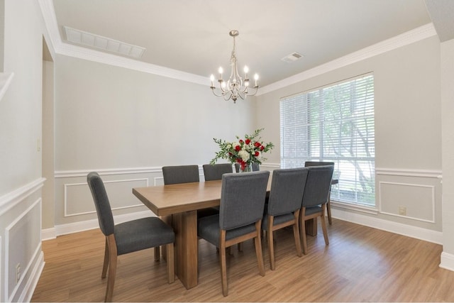 dining space featuring wood-type flooring, crown molding, and an inviting chandelier