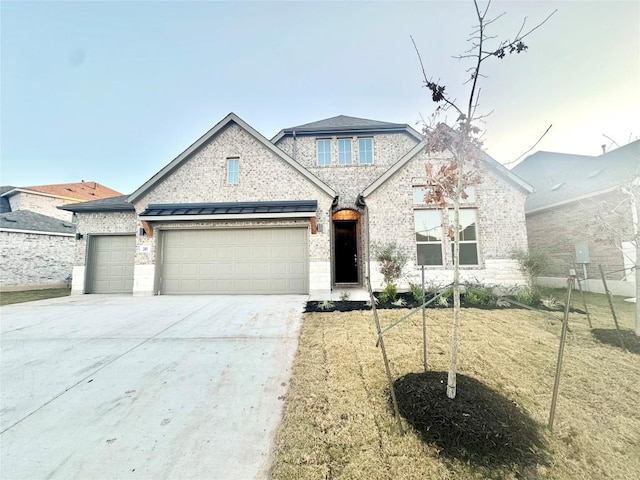 view of front of home with a front lawn, a standing seam roof, concrete driveway, a garage, and brick siding