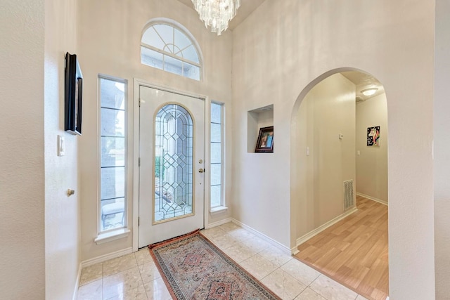 foyer with light hardwood / wood-style flooring, a high ceiling, and an inviting chandelier