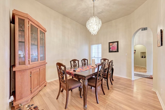 dining space featuring a notable chandelier, light wood-type flooring, and high vaulted ceiling