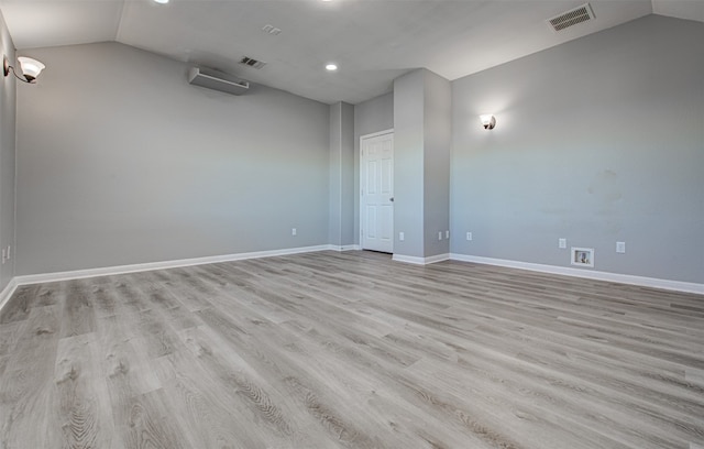 empty room with light hardwood / wood-style floors and vaulted ceiling